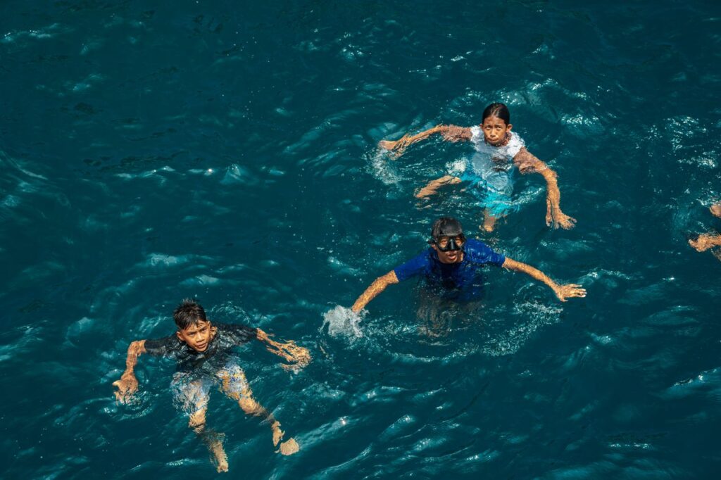 Family swimming together in blue ocean water, a highlight near the best family friendly hotels in East Bali