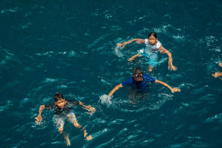 Family swimming together in blue ocean water, a highlight near the best family friendly hotels in East Bali