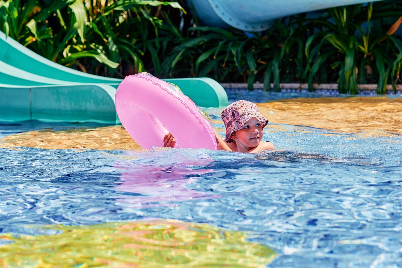 Child floating in a hotel pool next to a waterslide