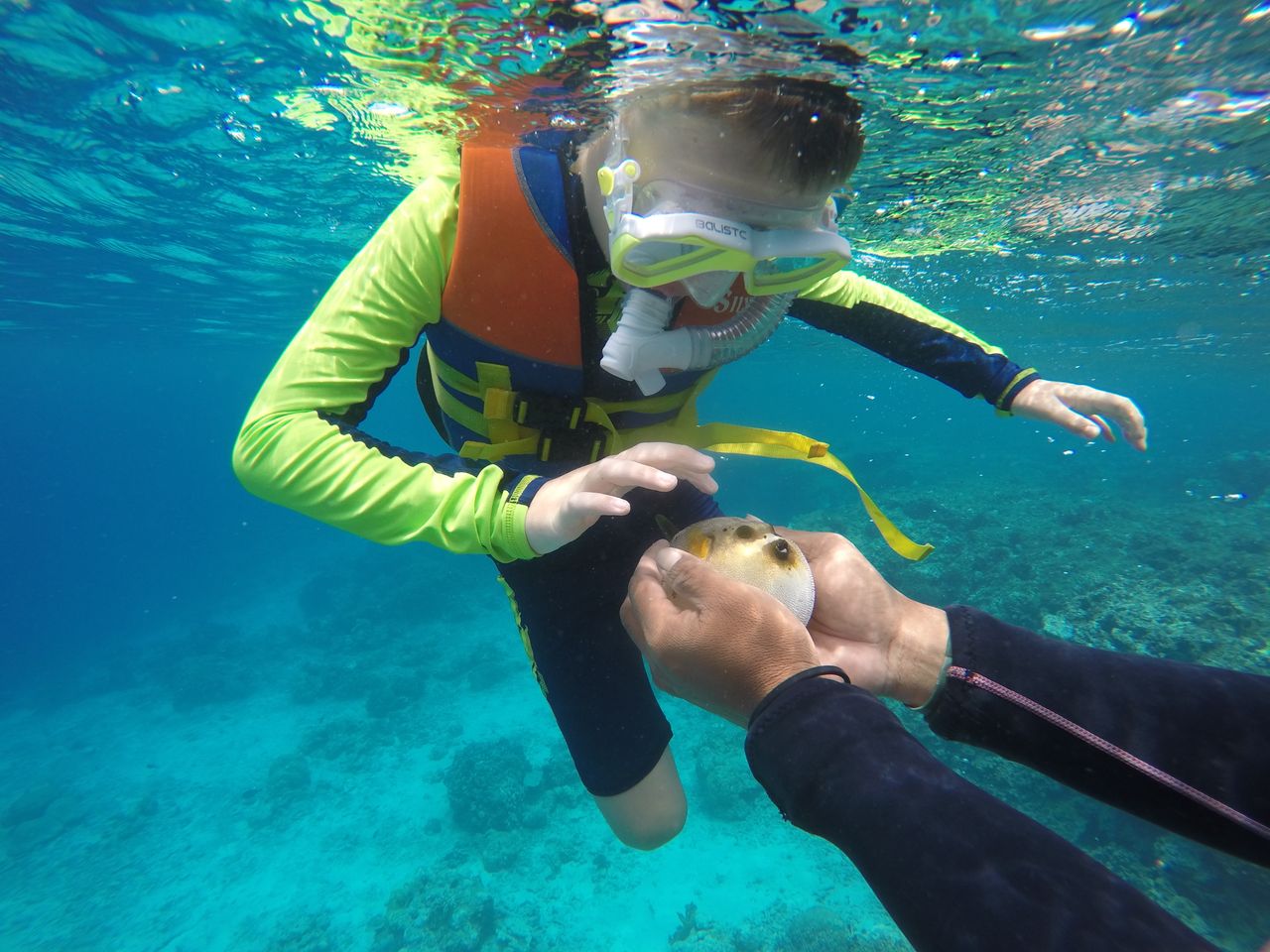 Child snorkeling with a parent in clear tropical water