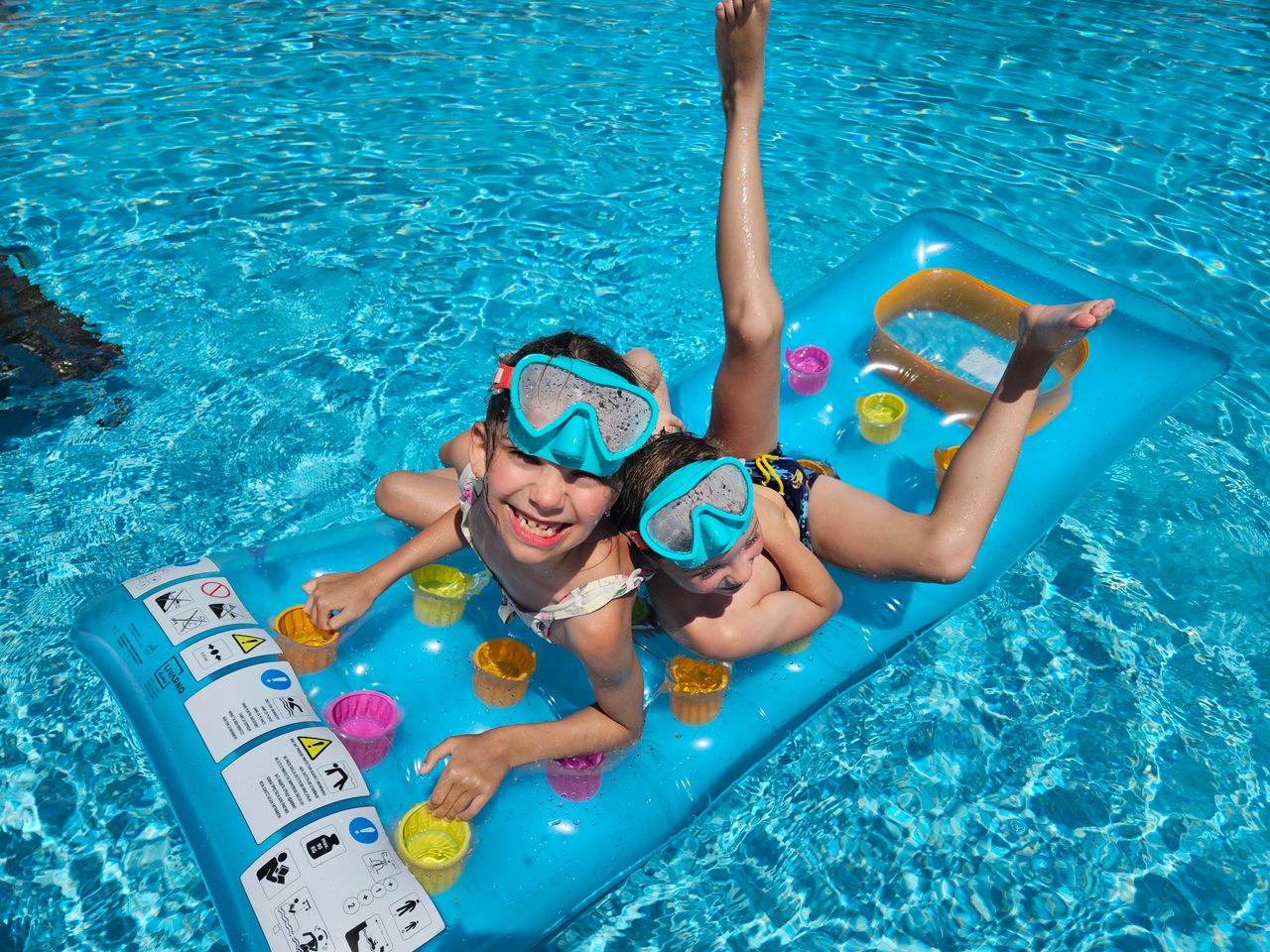 Two kids with snorkel masks relaxing on a pool float