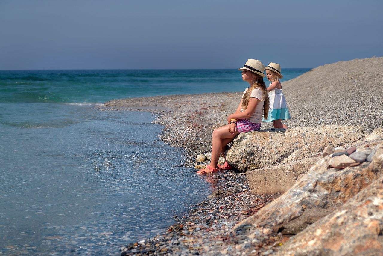 Mother and child sitting on the rocks by the sea