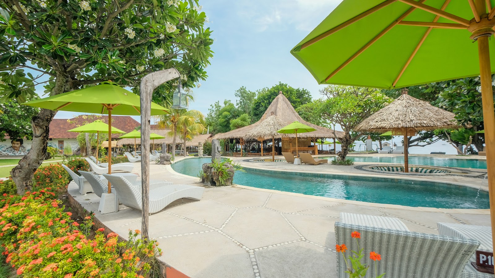 Poolside loungers under green umbrellas at Taman Sari Bali Resort